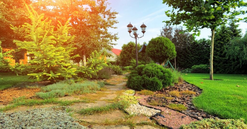 An landscaped yard with a decorative walkway and lamp post.